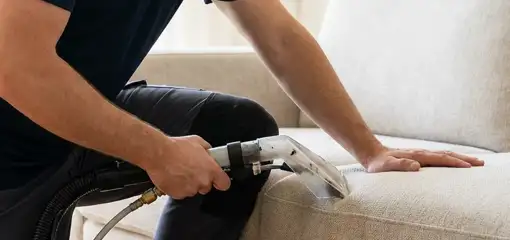 Professional upholstery cleaner deep-cleaning a fabric sofa with a handheld extraction tool, Fort Lauderdale, FL.